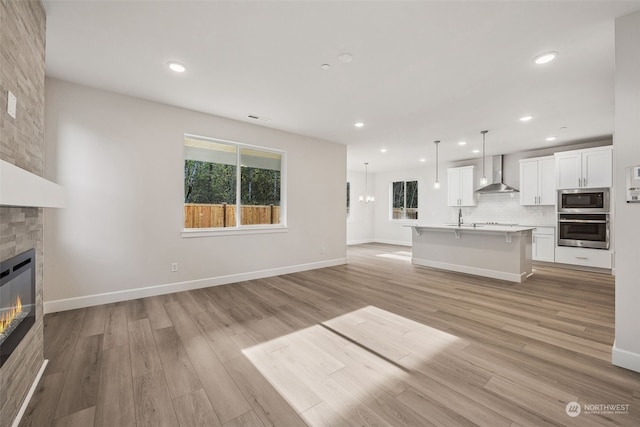 unfurnished living room with a healthy amount of sunlight, a fireplace, sink, and light wood-type flooring