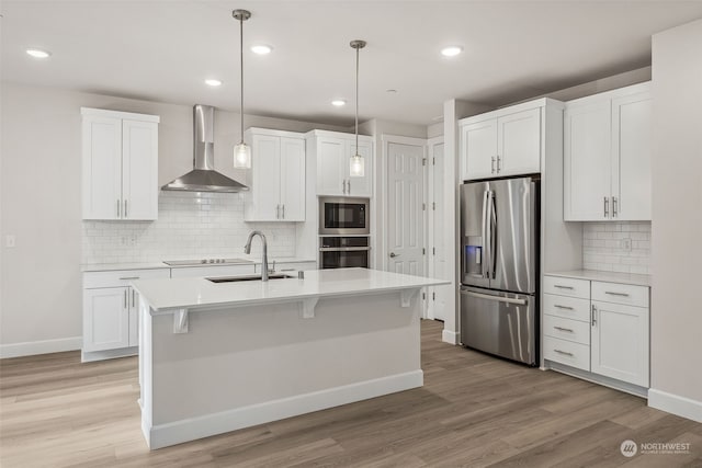 kitchen featuring pendant lighting, sink, black appliances, white cabinets, and wall chimney exhaust hood