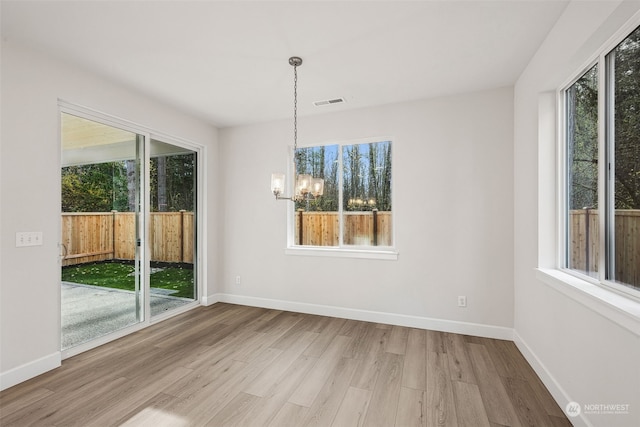 unfurnished dining area featuring hardwood / wood-style floors, a wealth of natural light, and a chandelier