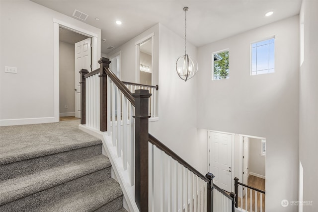 staircase featuring an inviting chandelier, a towering ceiling, and carpet flooring