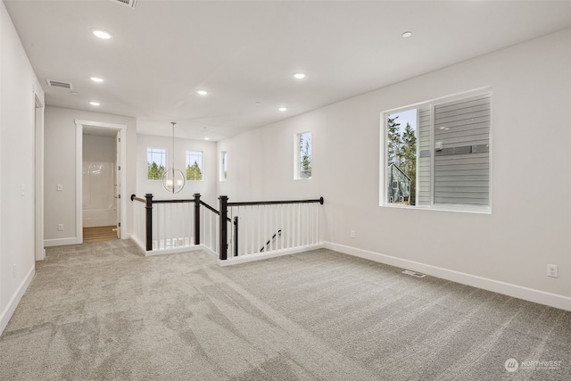 carpeted spare room featuring a chandelier