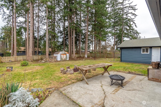 view of yard featuring an outdoor fire pit, a storage unit, and a patio area