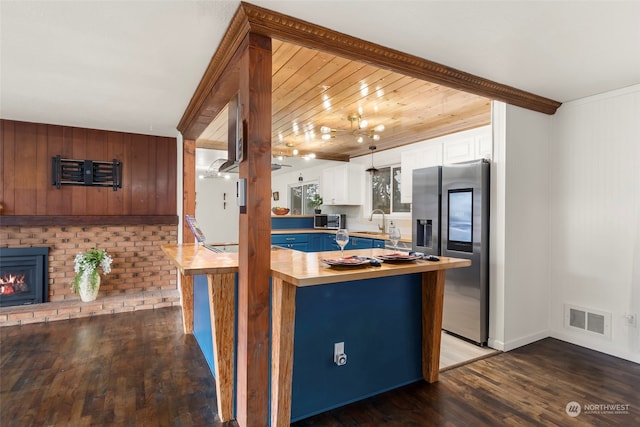 kitchen with a fireplace, white cabinetry, dark hardwood / wood-style flooring, kitchen peninsula, and stainless steel appliances