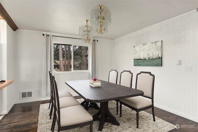 dining room featuring dark hardwood / wood-style flooring, ornamental molding, and an inviting chandelier