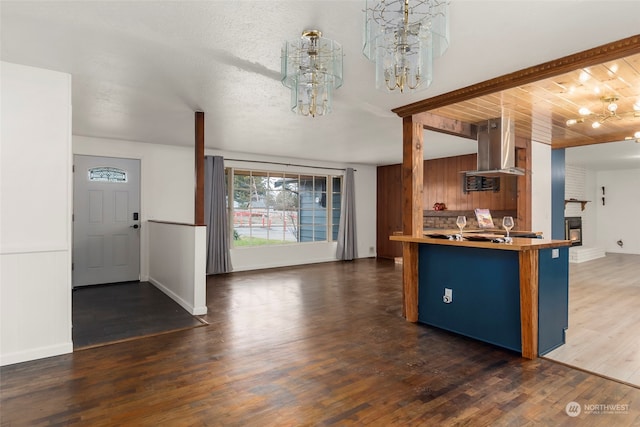 kitchen featuring ventilation hood, a kitchen bar, dark hardwood / wood-style flooring, a brick fireplace, and kitchen peninsula