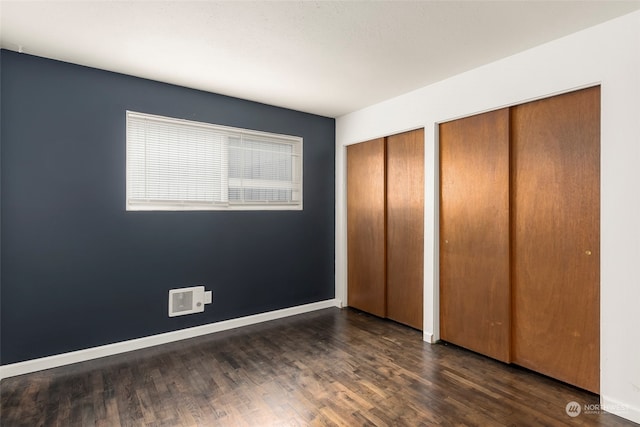 unfurnished bedroom featuring multiple closets and dark hardwood / wood-style floors