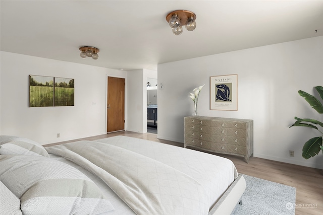 bedroom with light hardwood / wood-style floors and ensuite bathroom