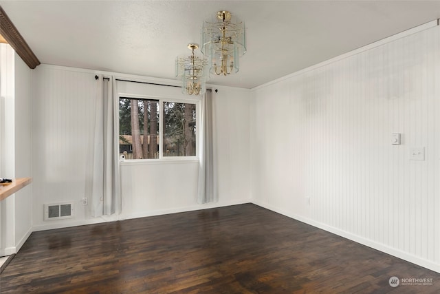 spare room with dark wood-type flooring, crown molding, and a chandelier