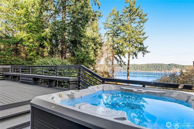 view of swimming pool with a forest view, a deck with water view, and a hot tub