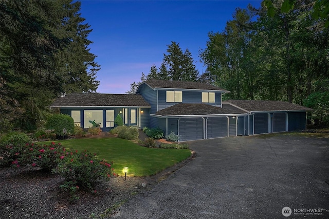 view of front of home featuring a front yard, an attached garage, and aphalt driveway