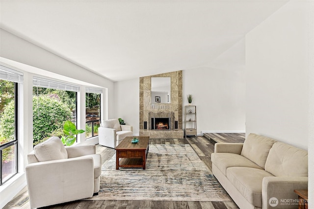 living area with a fireplace, lofted ceiling, wood finished floors, and visible vents