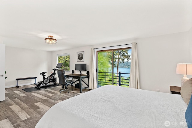 bedroom with access to exterior, multiple windows, and wood finished floors