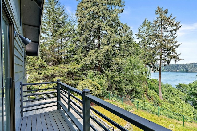 balcony featuring a wooded view and a water view