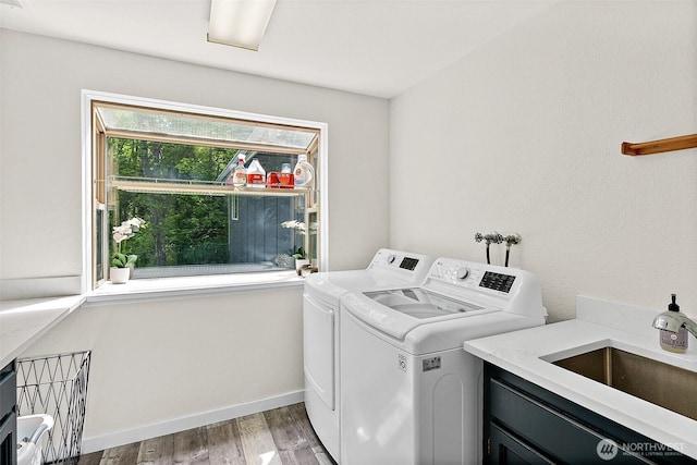 clothes washing area featuring baseboards, light wood finished floors, cabinet space, separate washer and dryer, and a sink