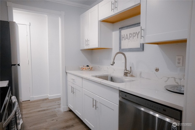 kitchen with sink, appliances with stainless steel finishes, light stone counters, light hardwood / wood-style floors, and white cabinets