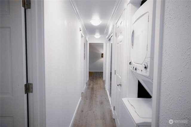 laundry room with ornamental molding, stacked washer and clothes dryer, and light wood-type flooring