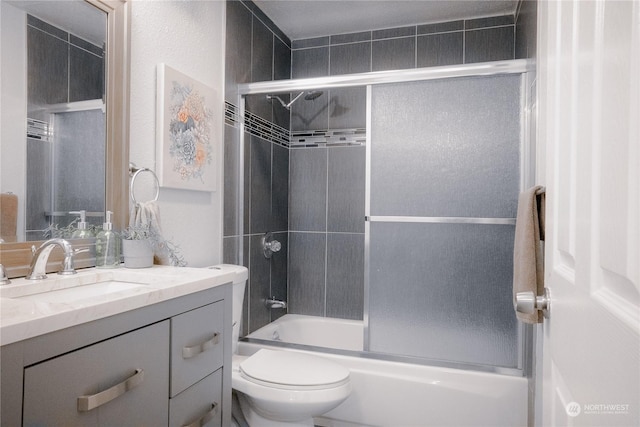 full bathroom with vanity, bath / shower combo with glass door, and toilet