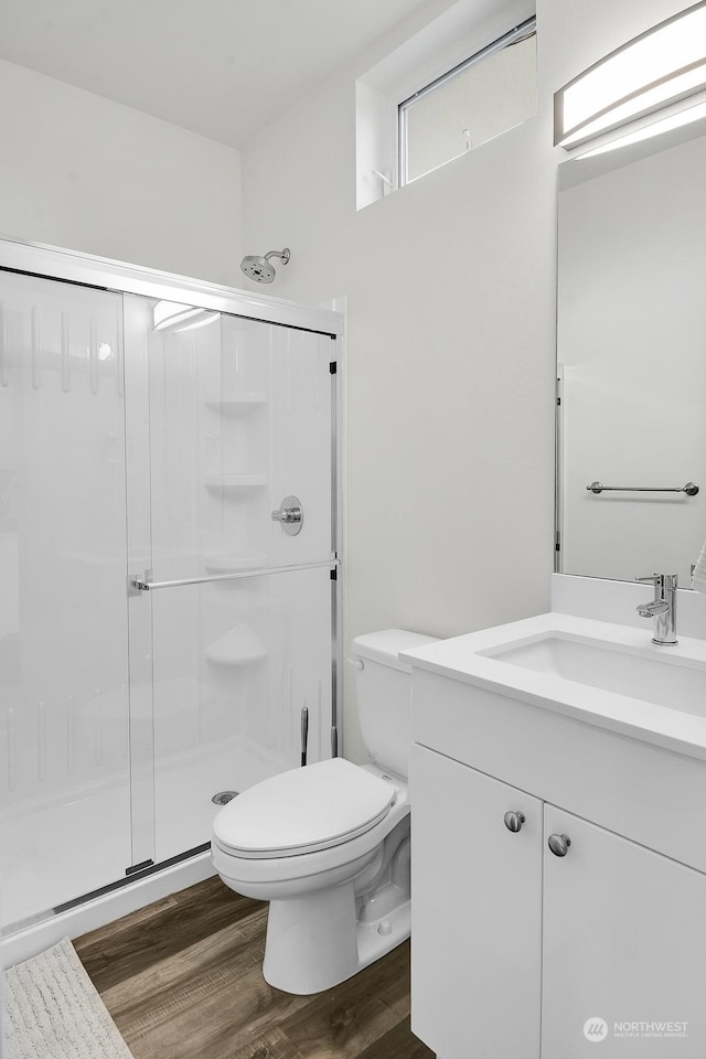 bathroom featuring toilet, hardwood / wood-style floors, vanity, and walk in shower