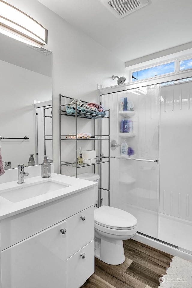 bathroom featuring hardwood / wood-style flooring, vanity, walk in shower, and toilet