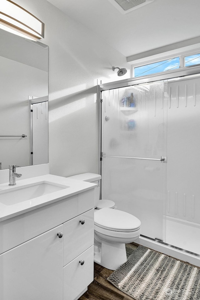 bathroom featuring vanity, an enclosed shower, hardwood / wood-style flooring, and toilet