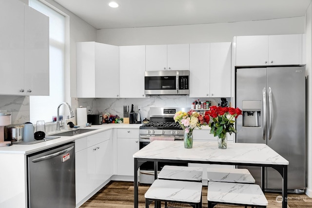 kitchen with appliances with stainless steel finishes, tasteful backsplash, white cabinetry, sink, and dark wood-type flooring