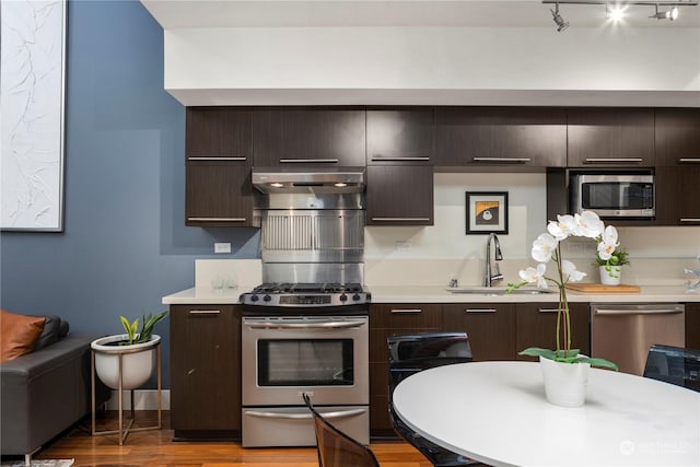 kitchen featuring stainless steel appliances, extractor fan, dark brown cabinets, and sink