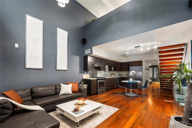 living room with dark wood-type flooring, sink, and a high ceiling