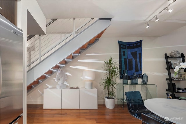 basement with rail lighting, stainless steel fridge, and dark hardwood / wood-style floors