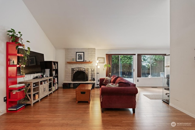 living room with lofted ceiling, a fireplace, and hardwood / wood-style floors