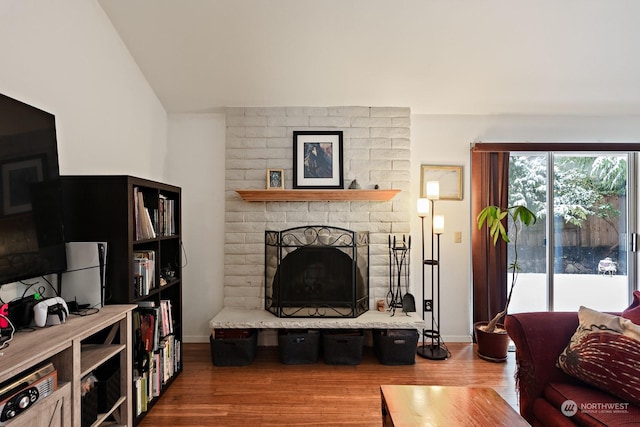 living room featuring hardwood / wood-style flooring, lofted ceiling, and a fireplace