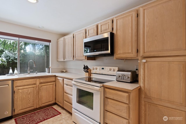 kitchen featuring stainless steel appliances, sink, light brown cabinets, and light tile patterned floors