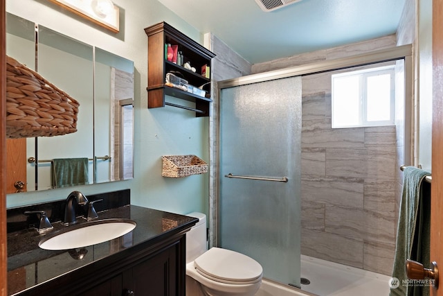 bathroom featuring vanity, a shower with door, and toilet