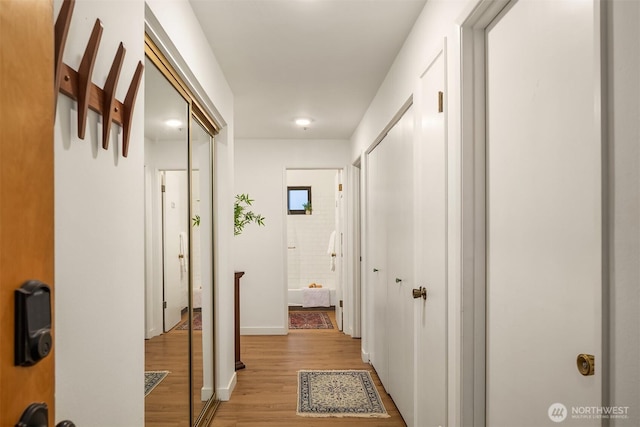 corridor featuring light wood finished floors and baseboards