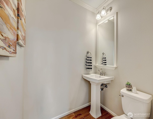 bathroom with crown molding, wood finished floors, toilet, and baseboards