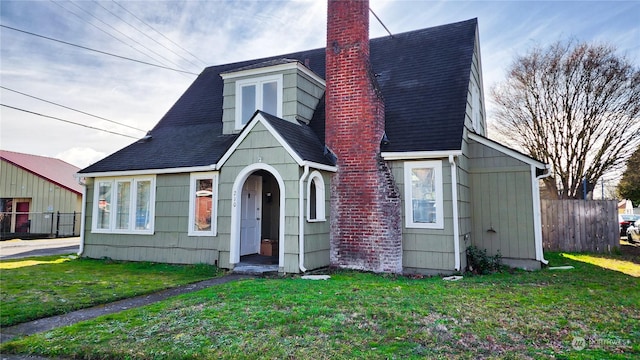 view of front of home featuring a shingled roof, a chimney, fence, and a front yard