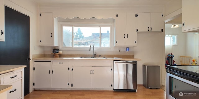 kitchen with stainless steel appliances, light countertops, white cabinets, and a sink