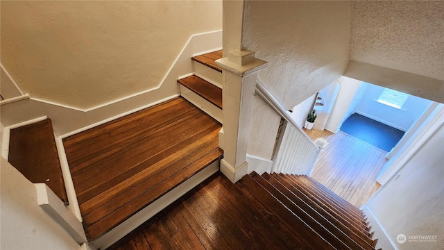 stairs featuring a textured wall and hardwood / wood-style floors