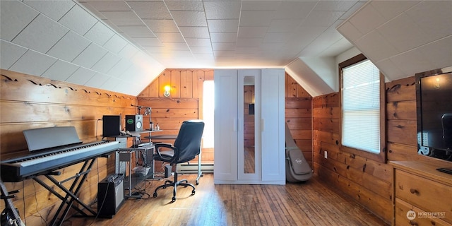 office space with baseboard heating, lofted ceiling, wood-type flooring, and wood walls