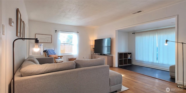 living room with a textured ceiling, wood finished floors, and visible vents