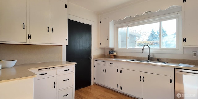 kitchen featuring light countertops, stainless steel dishwasher, white cabinetry, a sink, and light wood-type flooring