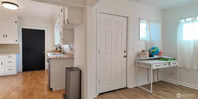 kitchen featuring light countertops, a sink, light wood-style flooring, and white cabinets