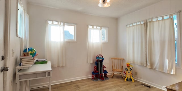 game room featuring visible vents, a textured ceiling, baseboards, and wood finished floors