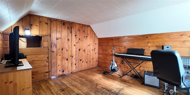 home office with vaulted ceiling, wood walls, and wood finished floors