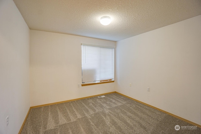 carpeted empty room featuring a textured ceiling