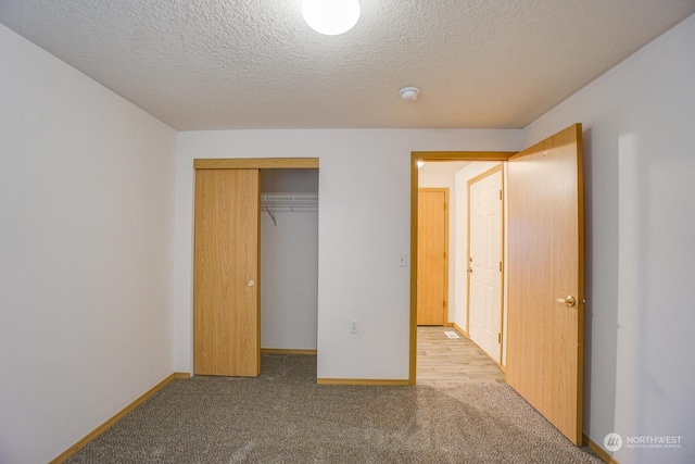 unfurnished bedroom featuring light colored carpet, a textured ceiling, and a closet