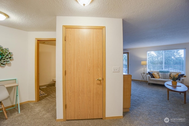 hall featuring a textured ceiling and carpet flooring