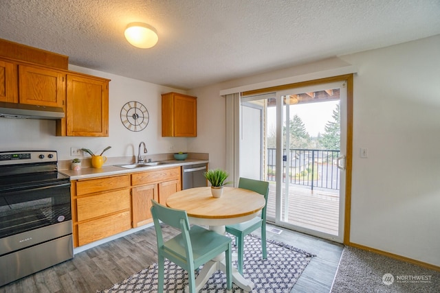 kitchen with sink, stainless steel appliances, light hardwood / wood-style floors, and a textured ceiling