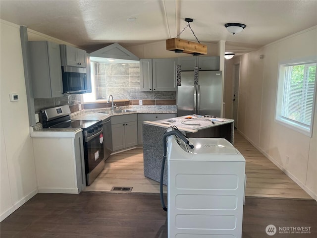 kitchen with light wood-type flooring, gray cabinets, tasteful backsplash, a sink, and appliances with stainless steel finishes