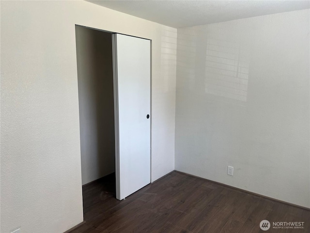 unfurnished bedroom with dark wood-style floors and a closet