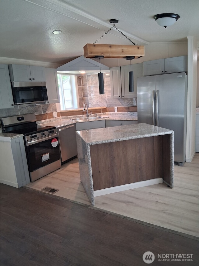 5591 Bethel Rd SE Unit 8, Port Orchard, WA 98367 - kitchen with stainless steel appliances, a kitchen island, a sink, light wood-style flooring, and a textured ceiling